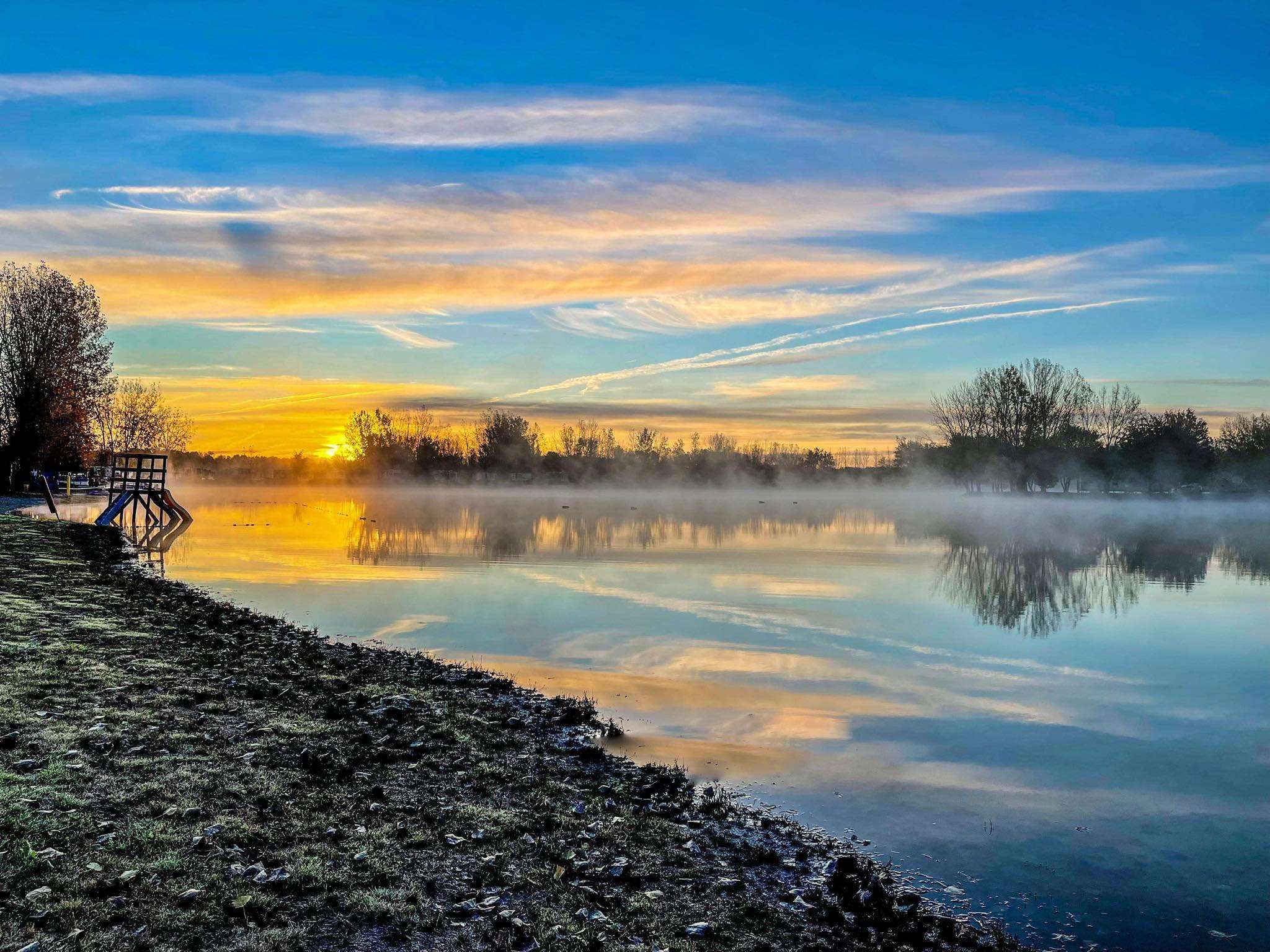 Misty sunrise over the lake with golden reflections